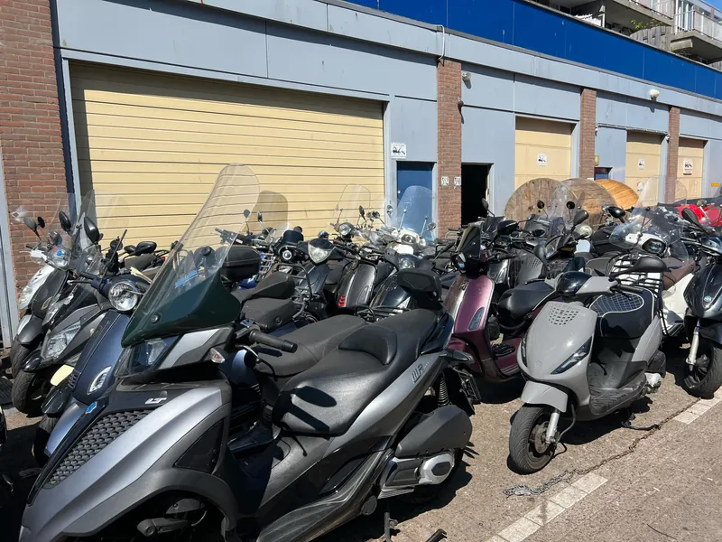Scooters geparkeerd voor de open roldeur van de werkplaats